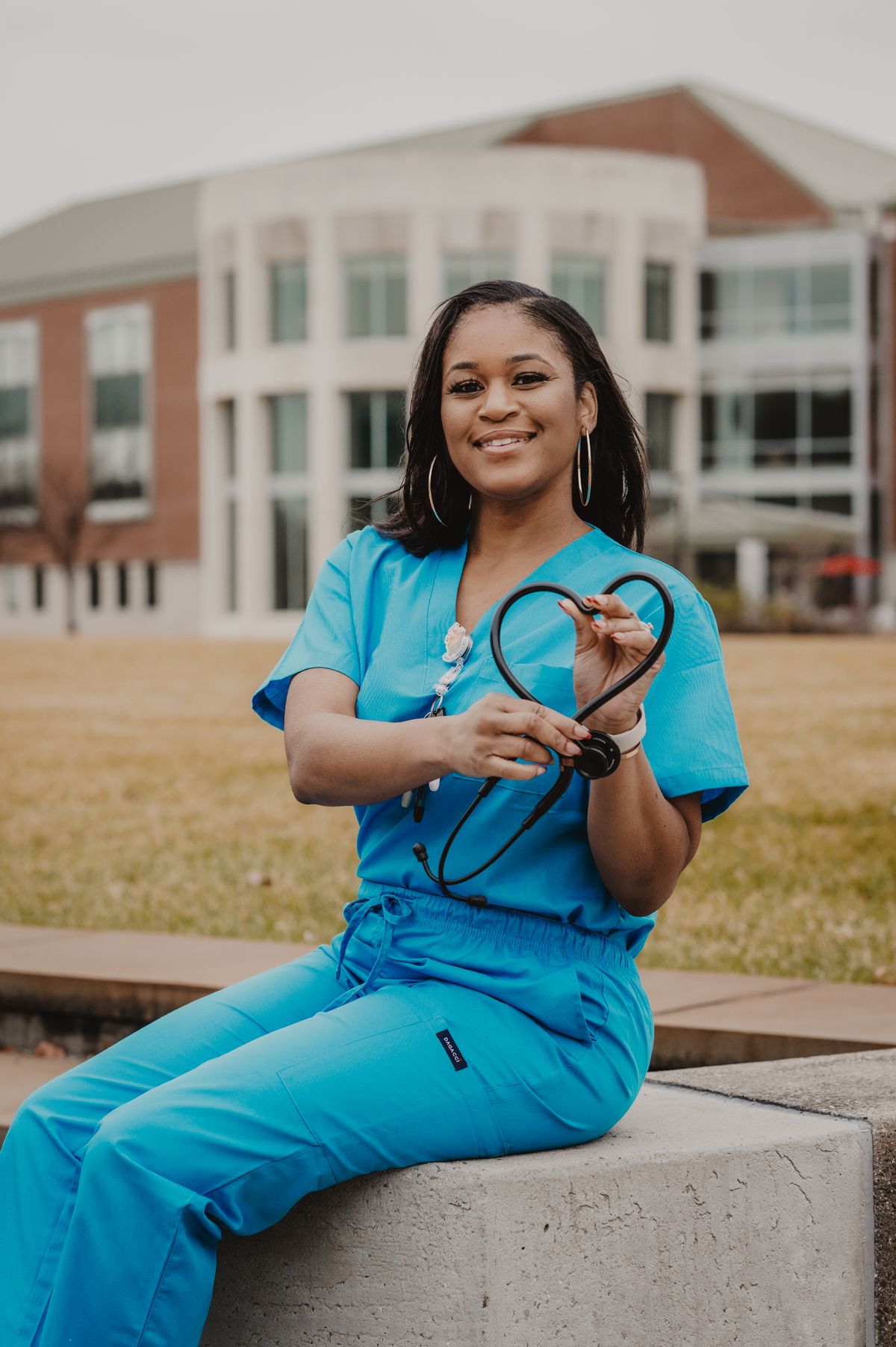 Doctor in scrubs forming a heart shape with a stethoscope